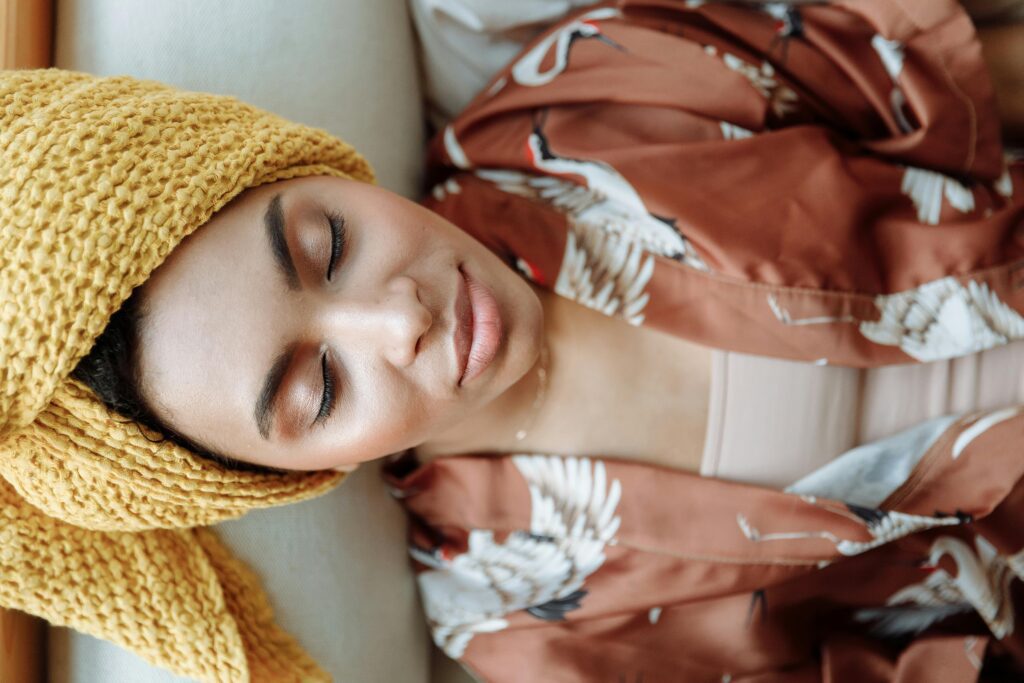 Mulher sentada em um ambiente tranquilo, praticando respiração consciente com olhos fechados, representando o equilíbrio emocional e o autocuidado diário.